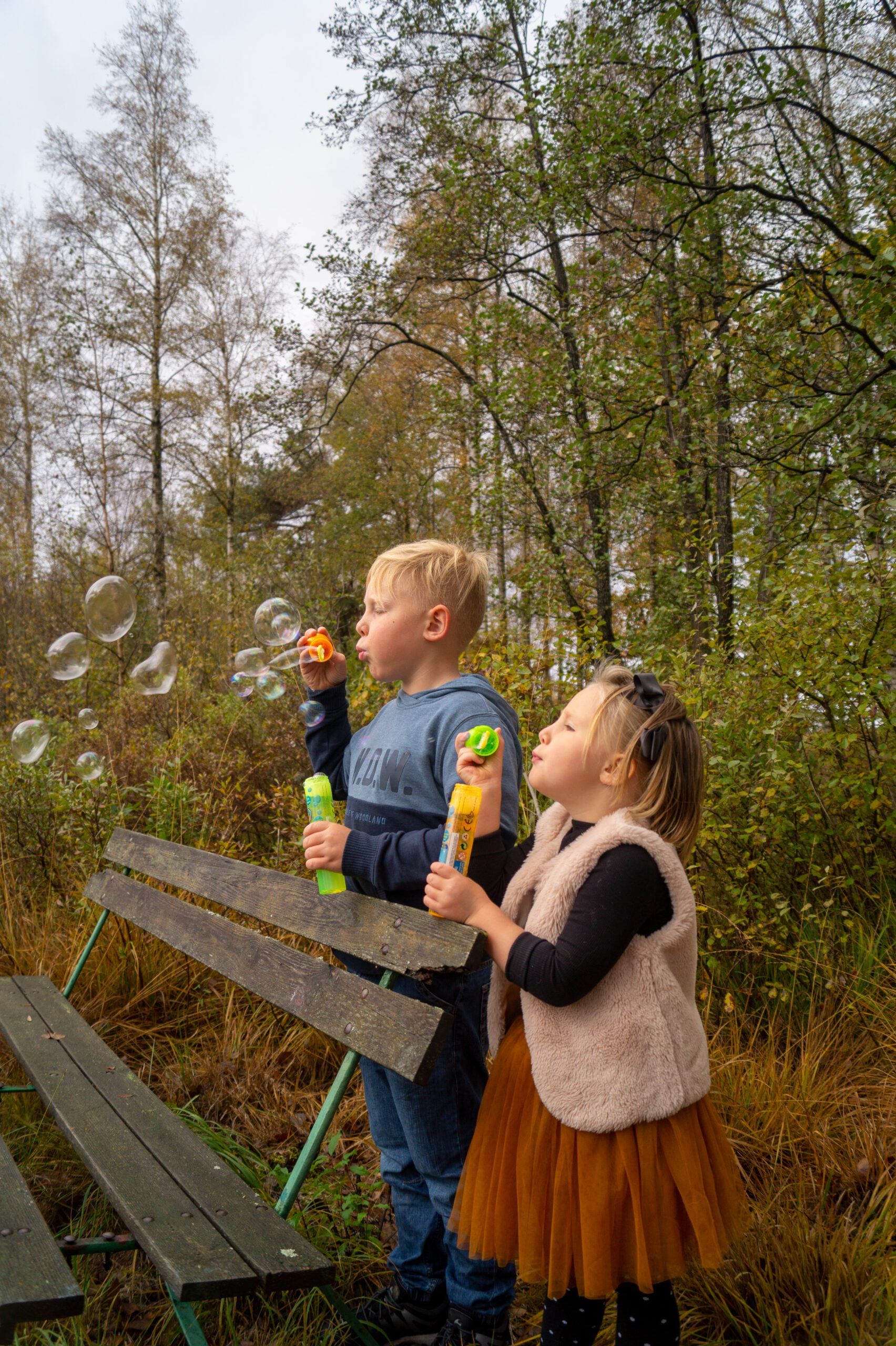 Bror och syster som blåser såpbubblor vid en bänk